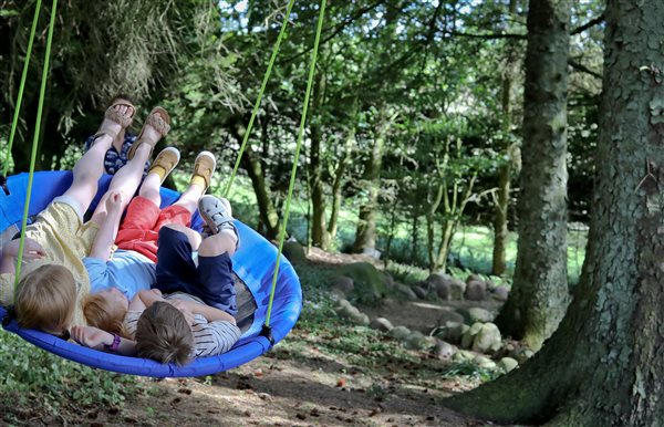 Three children playing on the tree swing at the rear of Cowden Farmhouse